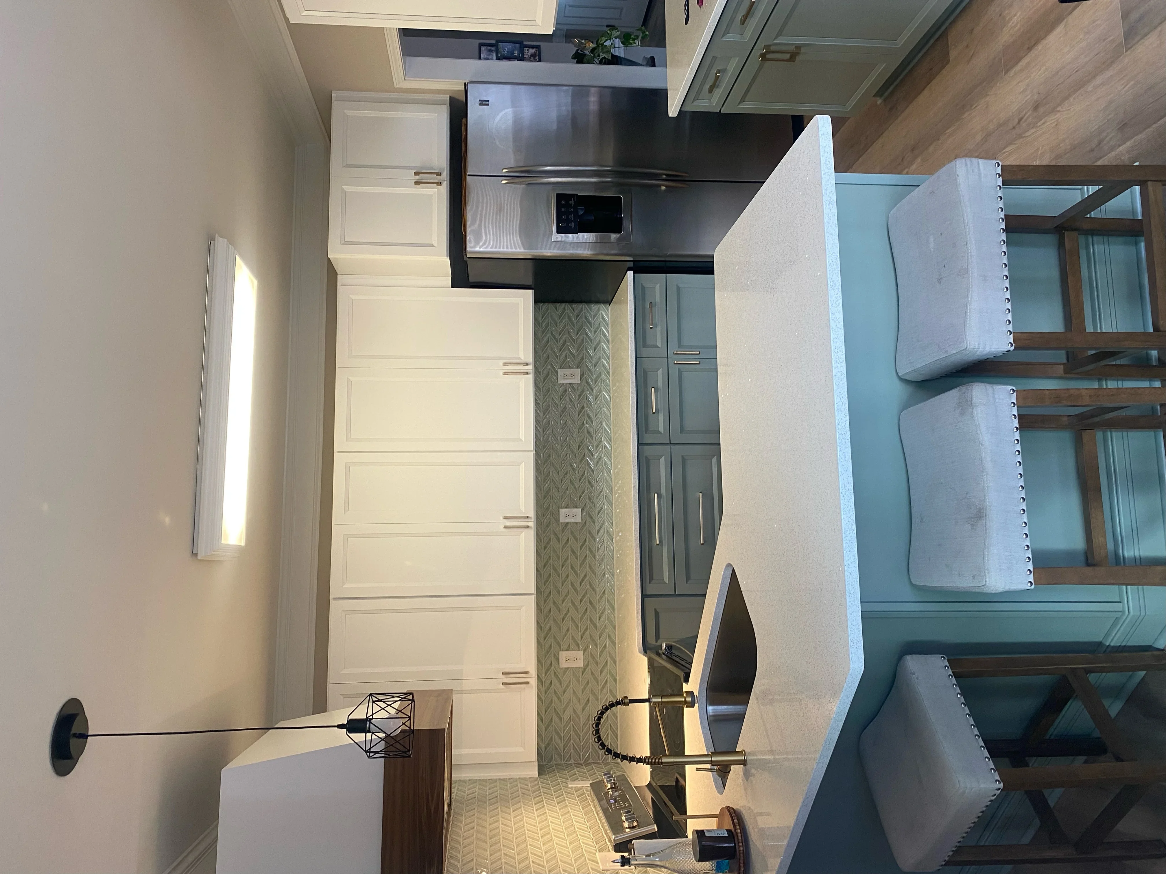 Kitchen with white cabinetry, herringbone backsplash, stainless steel appliances, and hardwood flooring