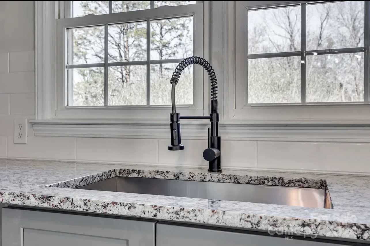 Stainless steel undermount sink with black pull-down faucet and speckled granite countertop