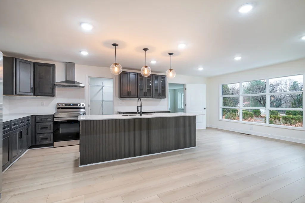 Modern kitchen with dark cabinetry, white quartz counters, island, pendant lights, and stainless appliances